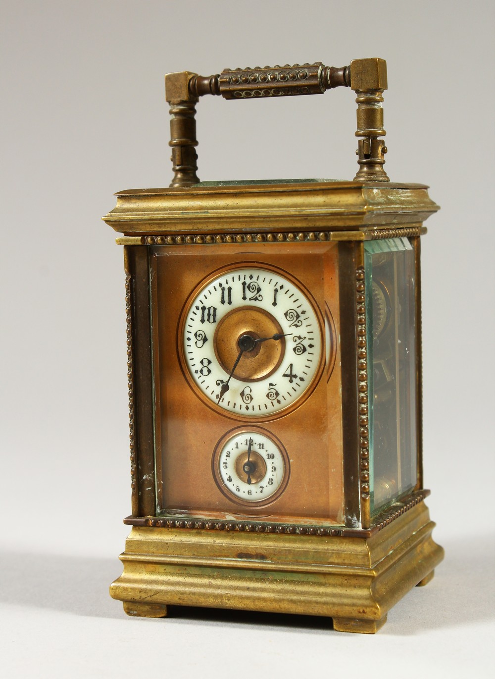 A MINIATURE BRASS CARRIAGE CLOCK, with alarm and subsidiary dial. 12cms high.