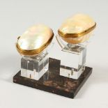 TWO MOTHER-OF-PEARL SHELL BOXES on a perspex stand.