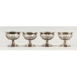 A SET OF FOUR FRENCH SILVER AND GLASS PEDESTAL SALTS.