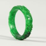 A CHINESE CARVED GREEN JADE BANGLE. 7.5cms diameter.