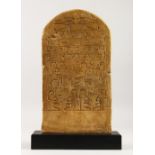 A MUSEUM COPY OF AN EGYPTIAN PLASTER ANTIQUITY on a wooden stand. 38cms high x 21cms wide.