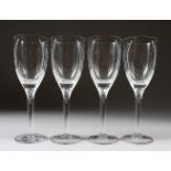 A SET OF FOUR LALIQUE CHAMPAGNE FLUTES with a moulded head. 20cms high. Engraved Lalique, France.