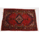 A PERSIAN RUG, dark red and blue ground, with a central large medallion. 200cms x 134cms.