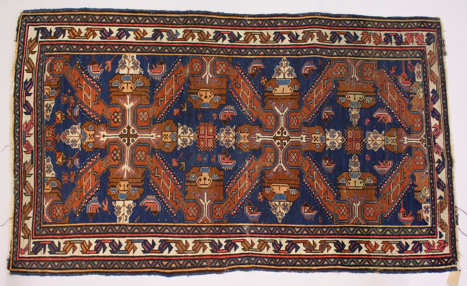 A PERSIAN RUG, blue ground with stylized motifs in a conforming border. 218cms x 130cms.