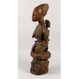 A YORUBA CARVED WOOD TRIBAL HEADDRESS with old patination, formed as a female figure, baby on her