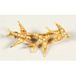 A GOLD AND SEED PEARL BROOCH MODELLED AS THREE SWALLOWS.