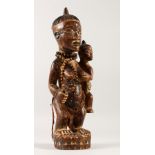 A TRIBAL WOOD CARVING, A MOTHER WITH A CHILD IN HER ARMS. 40cms high.