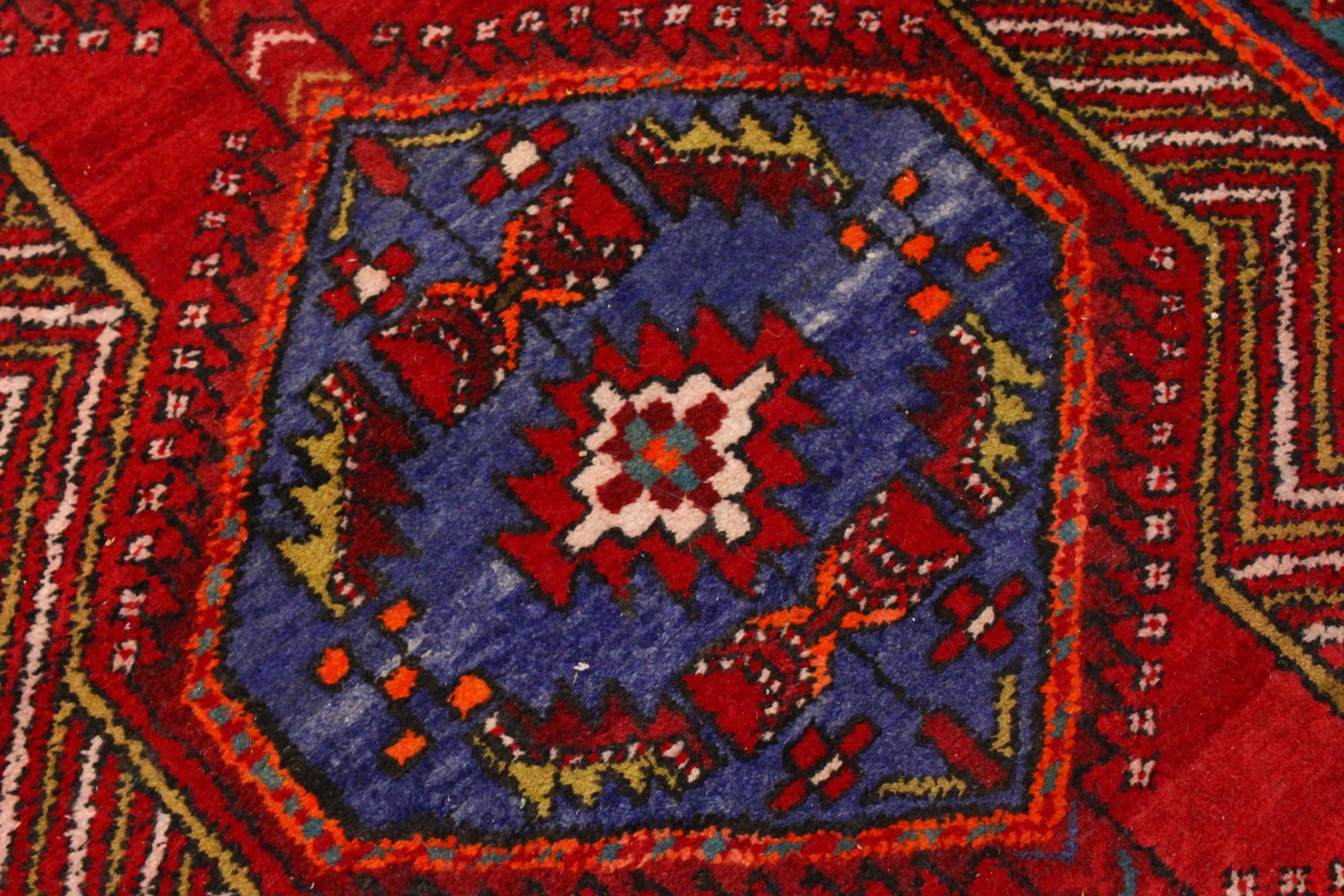 A PERSIAN LONG CARPET / RUNNER, bright red ground with three blue ground motifs in a stylized - Image 3 of 8