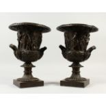 A PAIR OF BRONZE CAMPAGNA URNS, decorated with classical figures. 32cms high.