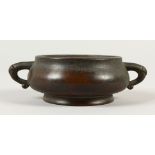 A CHINESE CIRCULAR BRONZE TWIN HANDLE CENSER, with nine character marks to the base. 14cms wide.