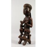 A GABON CARVED WOOD TRIBAL FERTILITY FIGURE from the Kota Tribe, mother and child sitting on a