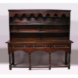 AN EARLY 17TH CENTURY OAK DRESSER, the upper section with shaped pelmet, and two shelves, the twin