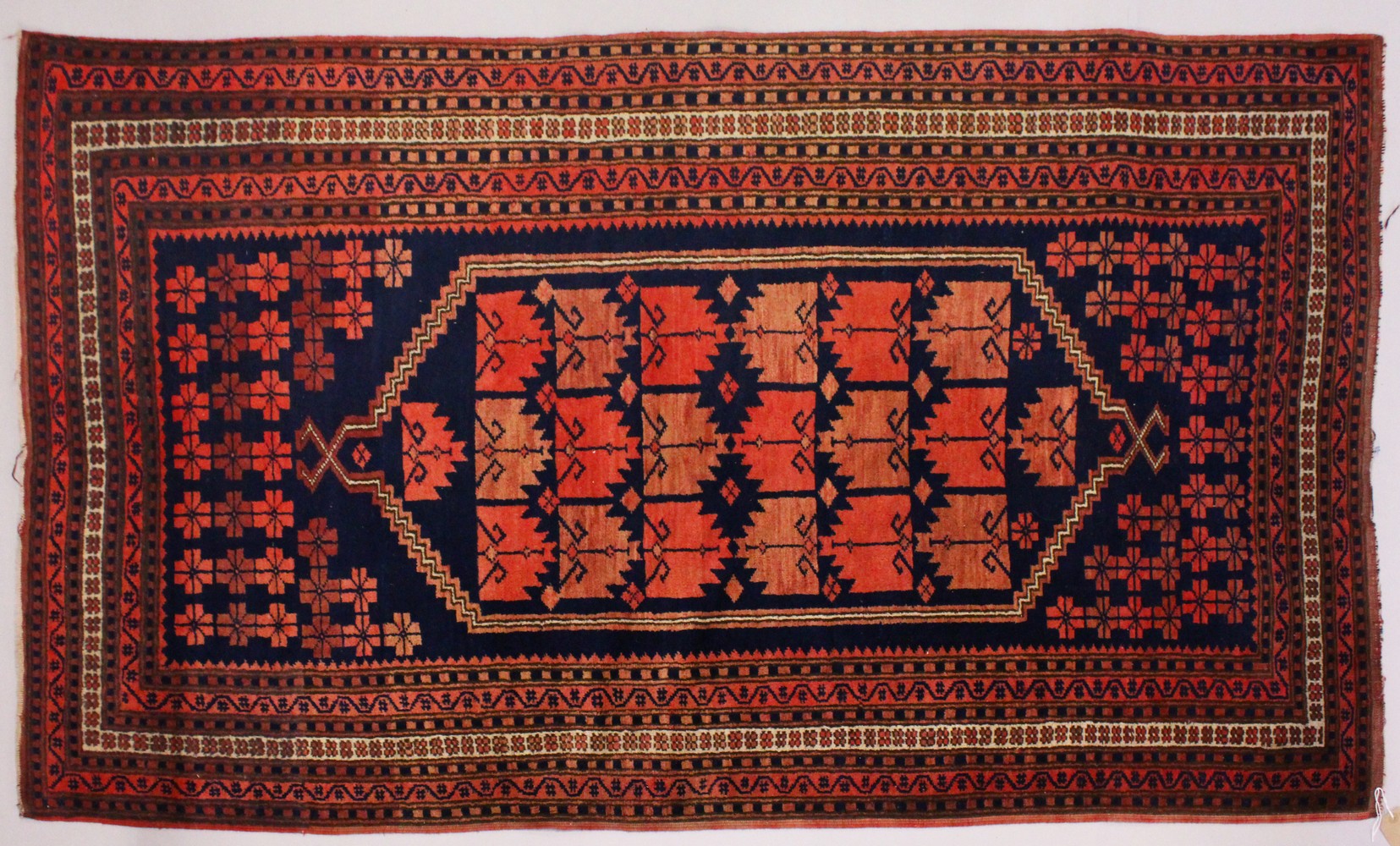 A PERSIAN RUG, dark blue ground, geometric motifs in a multiple border. 195cms x 110cms.