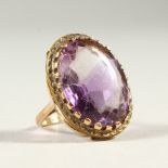 A GOLD RING SET WITH A LARGE AMETHYST COLOURED STONE.