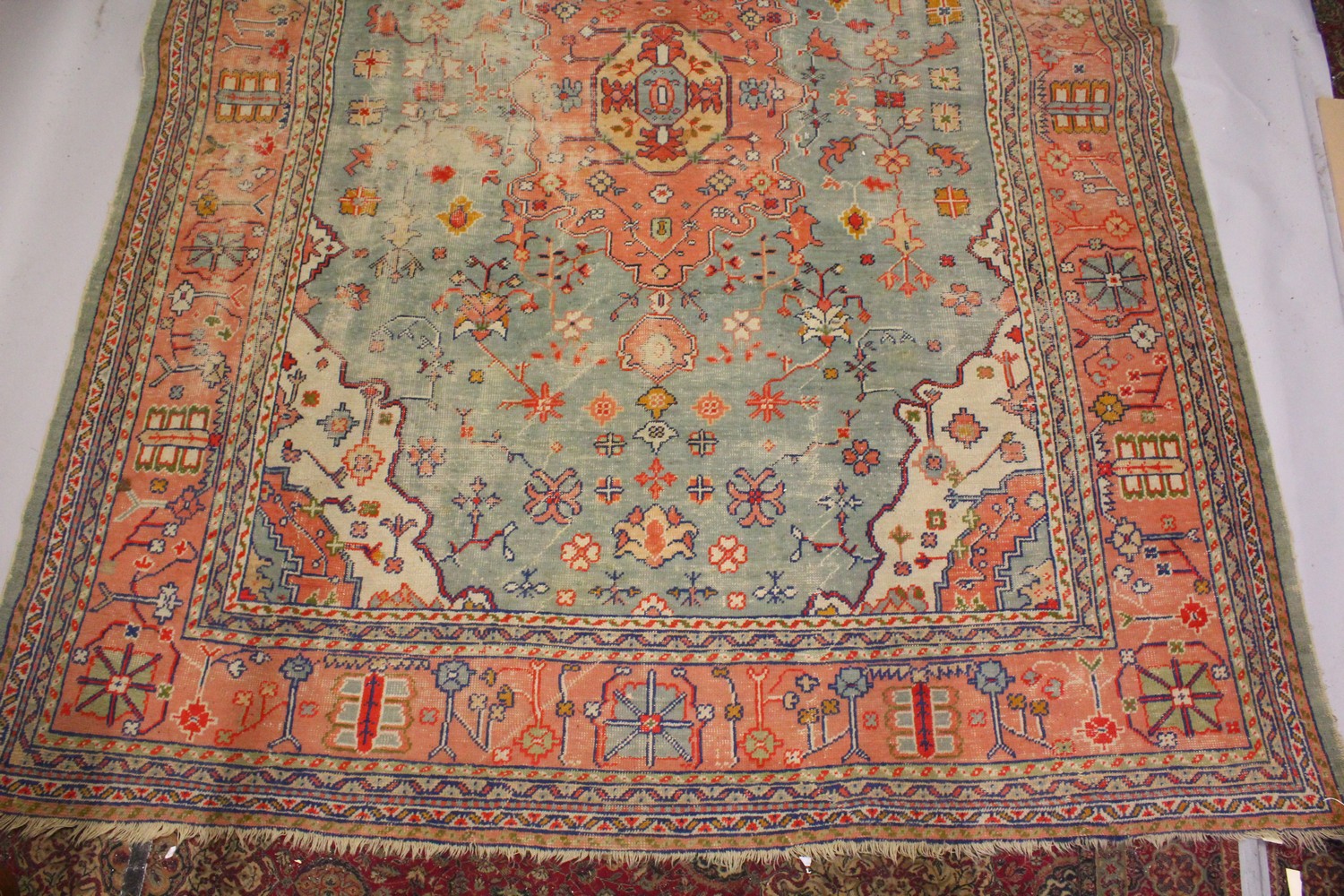 A LARGE HERIZ CARPET, pale blue ground, salmon pink central motif in a confirming border (worn). 4.