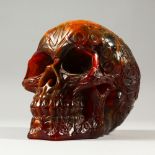 AN AMBER STYLE MODEL OF A HUMAN SKULL. 16cms wide.