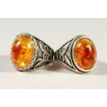 TWO SILVER AND AMBER RINGS.