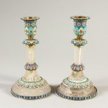 A PAIR OF RUSSIAN ROCK CRYSTAL AND CHAMPLEVE ENAMEL CIRCULAR CANDLESTICKS. 19cms high.