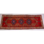 A PERSIAN LONG CARPET / RUNNER, bright red ground with three blue ground motifs in a stylized