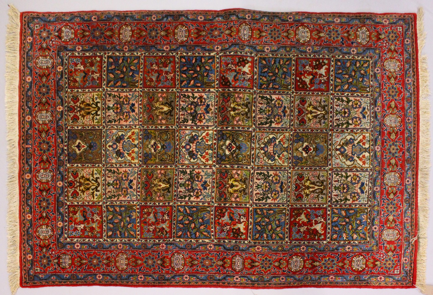 A GOOD PERSIAN RUG, with five rows of eight panels, each decorated with trees and flowers, in a