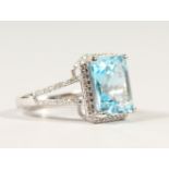 A 14K WHITE GOLD AND DIAMOND RING, set with an emerald cut blue topaz approx. 5.29ct, diamonds
