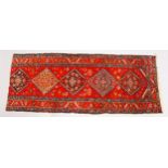 A PERSIAN LONG CARPET, bright red ground with five large medallions (reduced in length). 294cms x