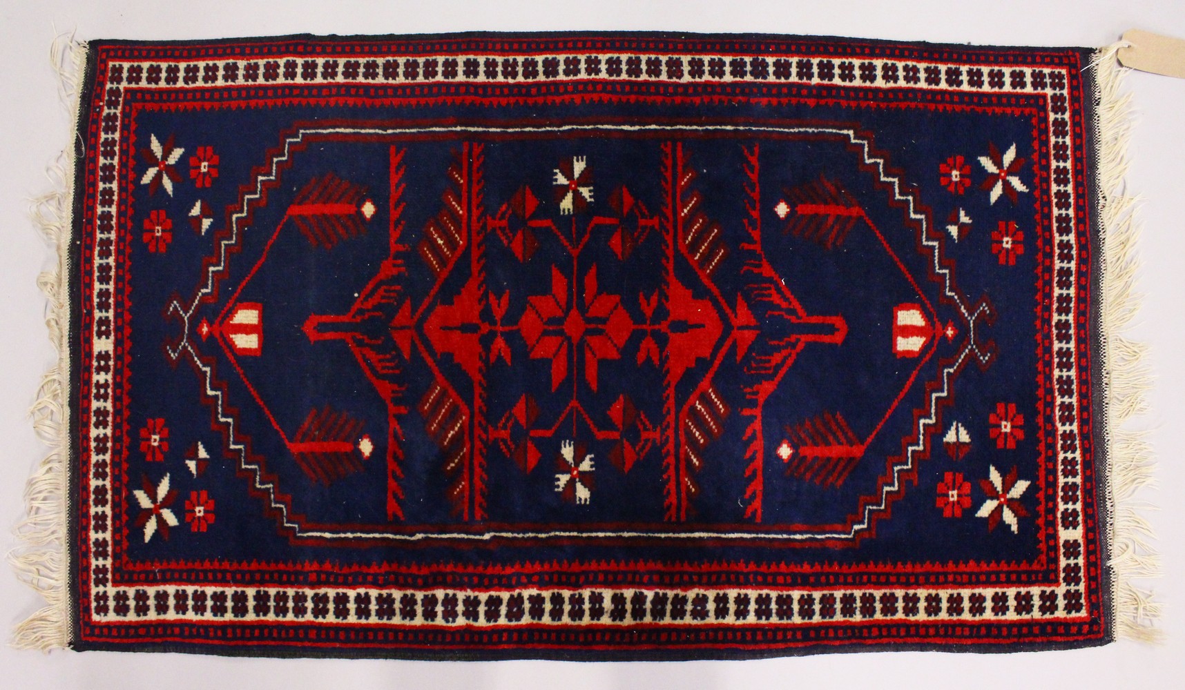 A SMALL PERSIAN RUG, dark blue ground with stylized decoration. 125cms x 75cms.