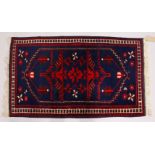 A SMALL PERSIAN RUG, dark blue ground with stylized decoration. 125cms x 75cms.