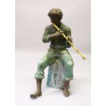 A NEAR LIFE SIZE BRONZE FIGURE OF A BOY seated on a rock, playing a flute. 126cms high.