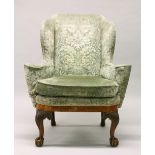 A GEORGE II / III WALNUT WING ARMCHAIR, with a veneered apron, acanthus carved legs ending in claw