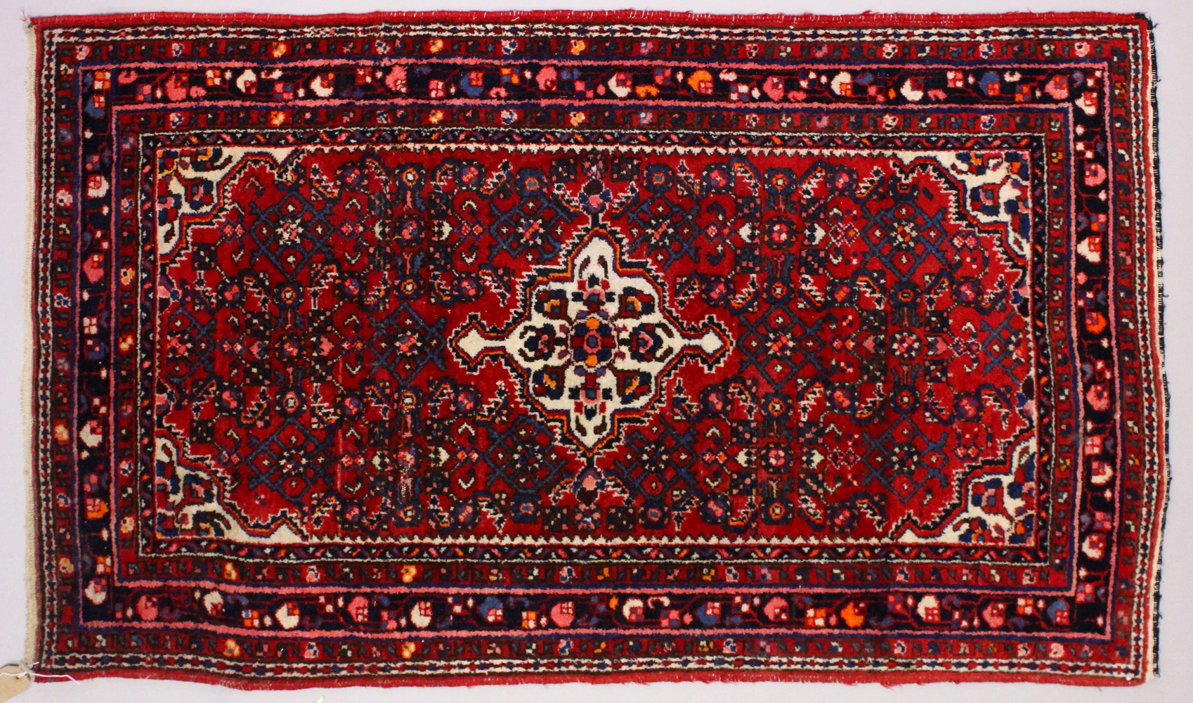 A PERSIAN RUG, red ground with central motif and similar border. 150cms x 105cms.