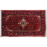 A PERSIAN RUG, red ground with central motif and similar border. 150cms x 105cms.