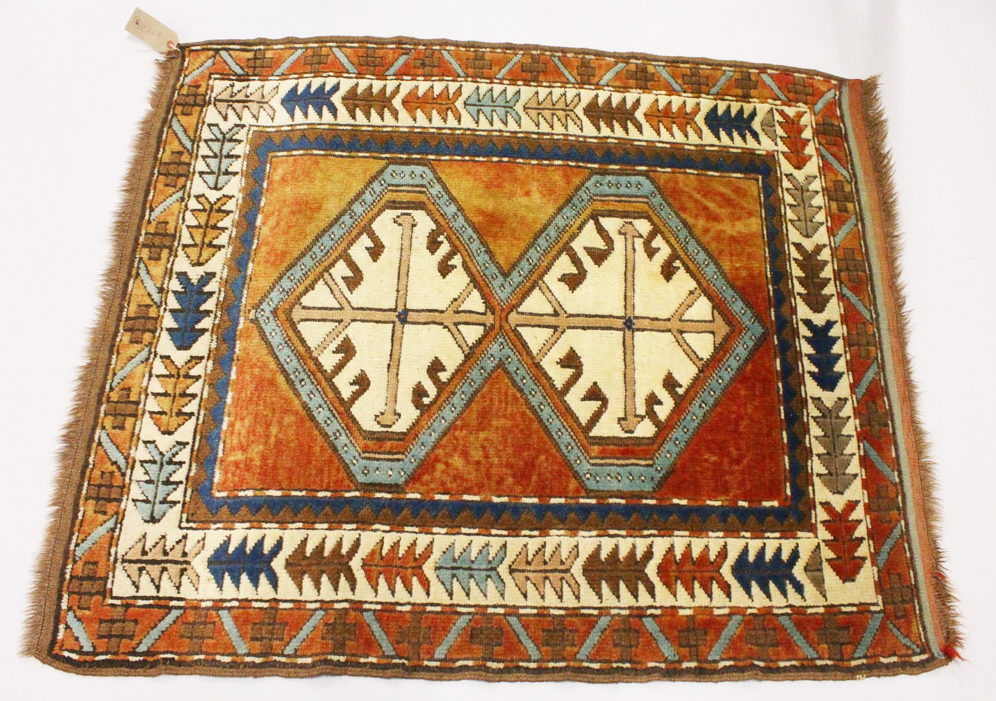 A SMALL PERSIAN RUG, the centre with two large geometric motifs, in a border with stylised tree