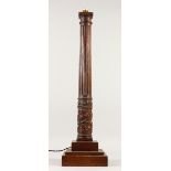 A 19TH CENTURY TURNED AND CARVED WOOD LAMP BASE, on a square base. 74cms high.