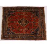 A PERSIAN RUG, rust ground with central motifs, floral decorated border. 160cms x 125cms.