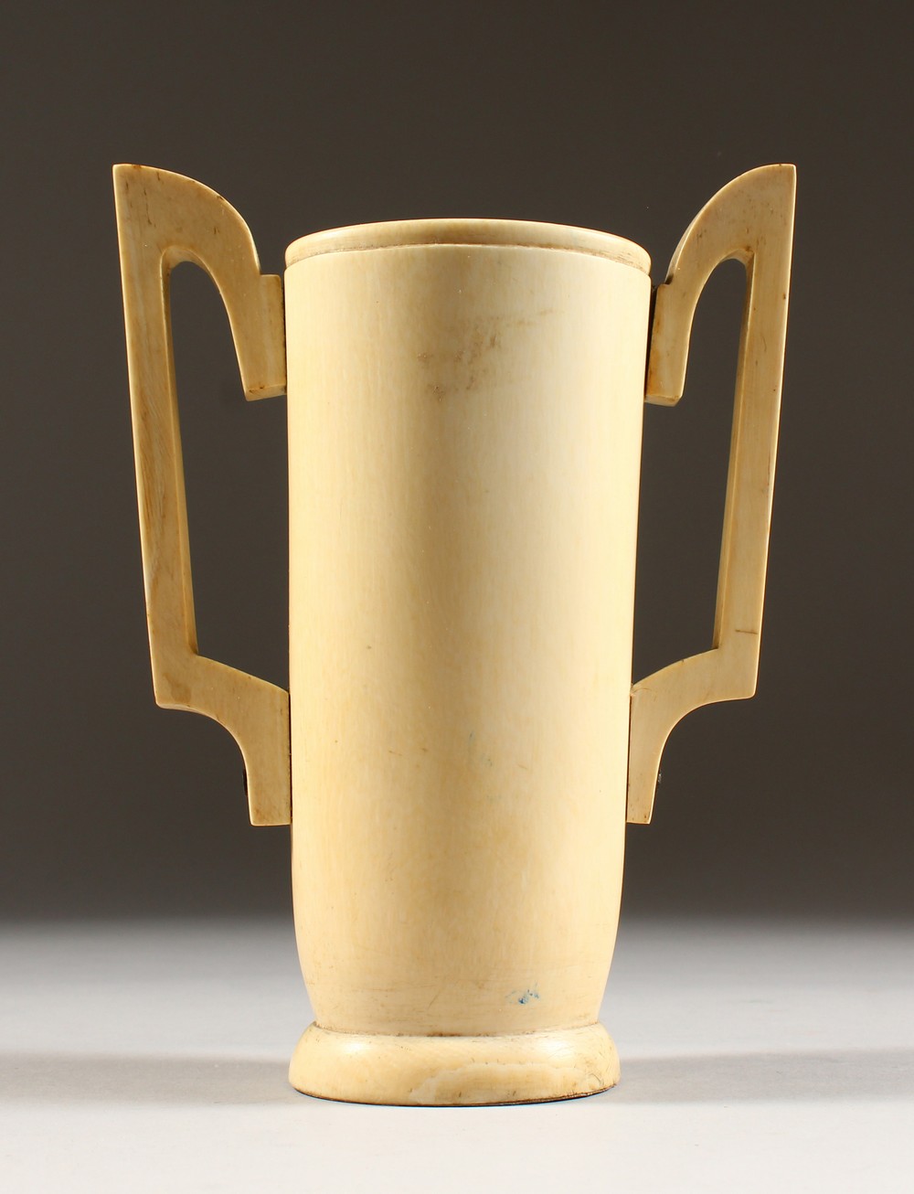 AN IVORY TWO HANDLED TUSK VASE. 7ins high.