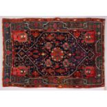 A PERSIAN RUG, blue ground with stylized motifs in a green ground border. 200cms x 140cms.