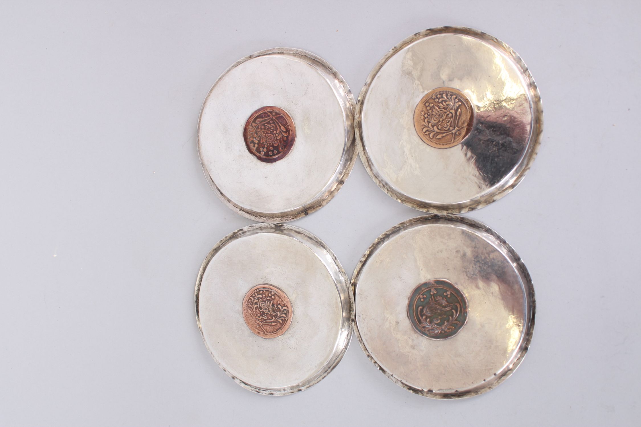 A SET OF FOUR ISLAMIC SILVER CIRCULAR DISHES inserted with coins, 11cm diameter. - Image 6 of 6