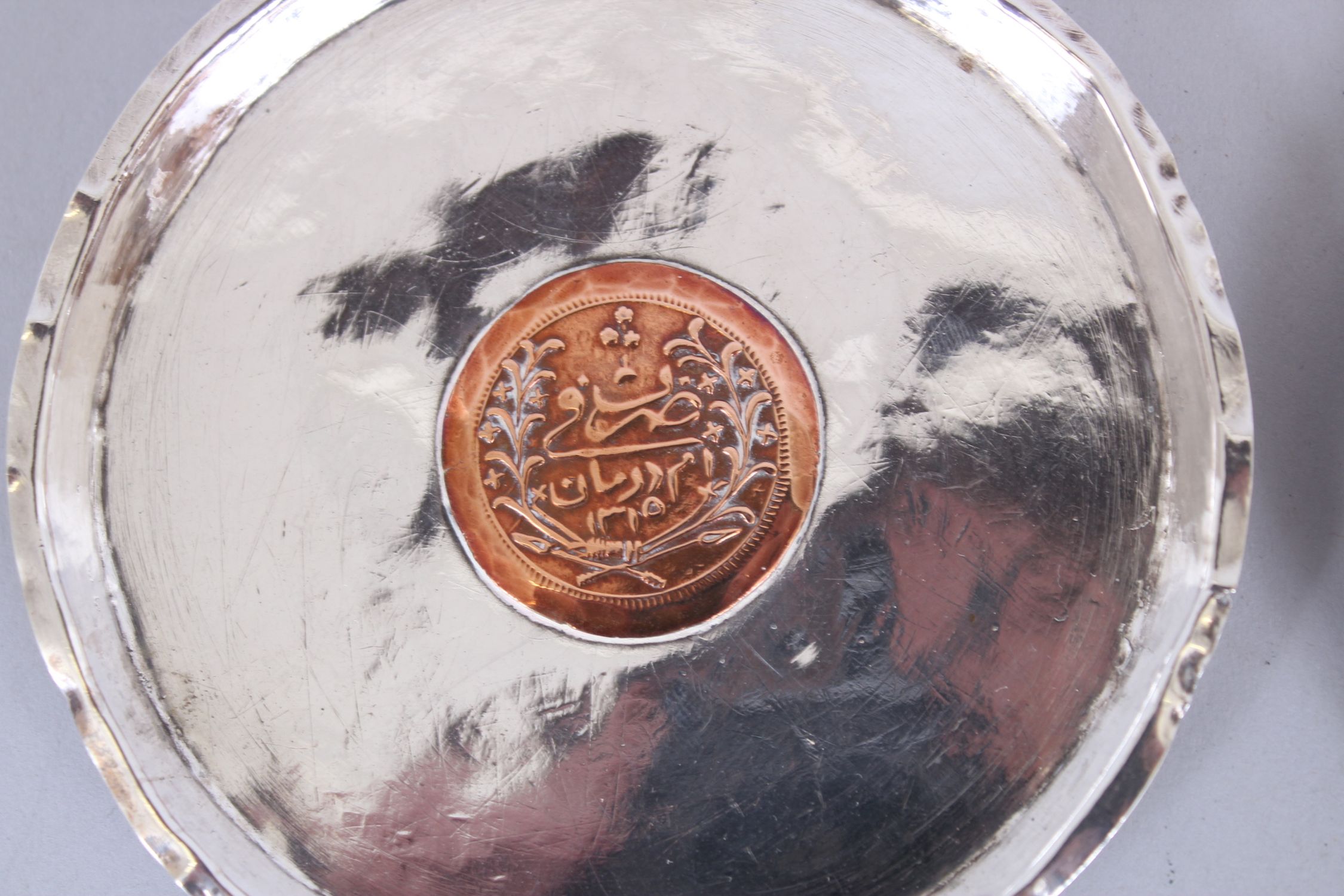 A SET OF FOUR ISLAMIC SILVER CIRCULAR DISHES inserted with coins, 11cm diameter. - Image 4 of 6