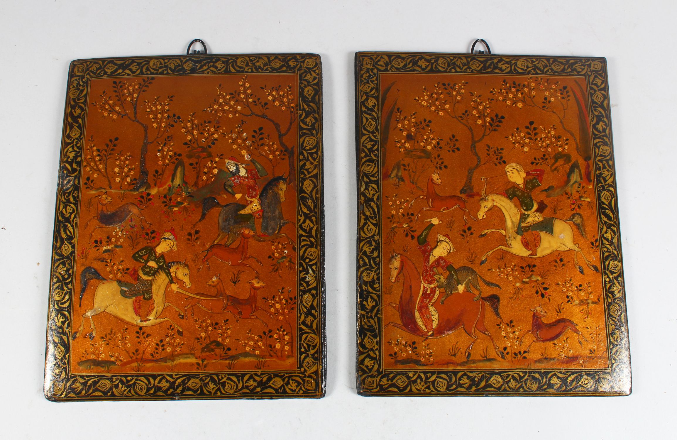 A PAIR OF 19TH CENTURY QAJAR HAND PAINTED BOOK COVERS, deer hunting, 26cm x 19cm.