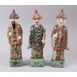 THREE EARLY 20TH CENTURY FAMILLE ROSE PORCELAIN FIGURES OF OFFICIALS, each stood upon a formed grass