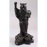 A 19TH CENTURY CHINESE BRONZE FIGURE OF LOUHAN, stood upon a rocky ourcrop with his hand aloft,