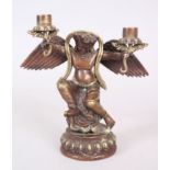 AN EARLY TIBETAN BRONZE CANDLESTICK as a god with wings and outstretched arms, 21cm high.
