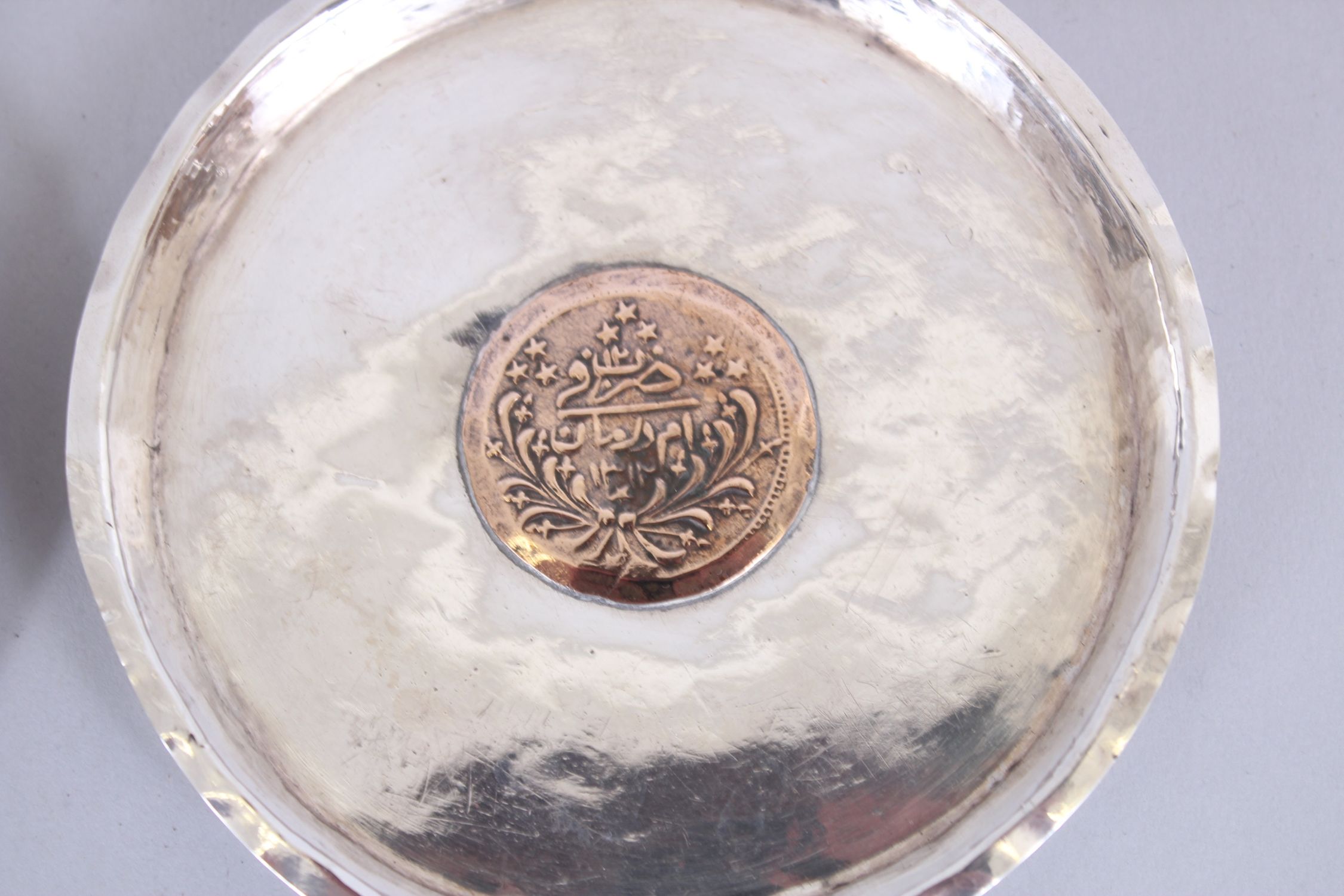 A SET OF FOUR ISLAMIC SILVER CIRCULAR DISHES inserted with coins, 11cm diameter. - Image 5 of 6