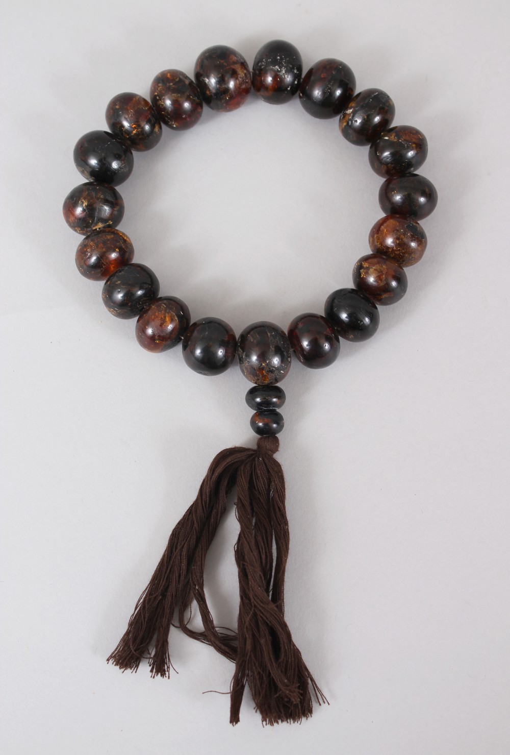 A GOOD CHINESE CHERRY AMBER BRACELET / NECKLACE, comprising of 21 spherical beads of assorted sizes,