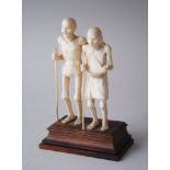 AN INDIAN IVORY GROUP OF TWO FIGURES on a wooden stand, 11cm high.