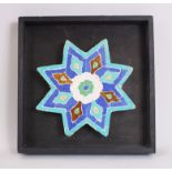 A FINE 17TH CENTURY OR EARLIER PERSIAN STAR SHAPED MOSAIC TILE, 21cm on a wooden surround.