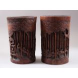 A PAIR OF CHINESE 19TH CENTURY BAMBOO CARVED BRUSH POTS, carved deeply to depict scenes of figures