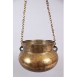 AN ISLAMIC CIRCULAR BRASS BOWL with chains, 21cm wide.