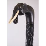 A CEYLONESE CARVED EBONY ELEPHANT HANDLE WALKING STICK, 88cm long.